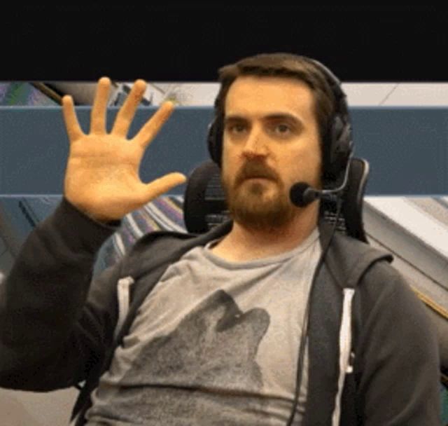 a man wearing headphones and a wolf t-shirt waves his hand