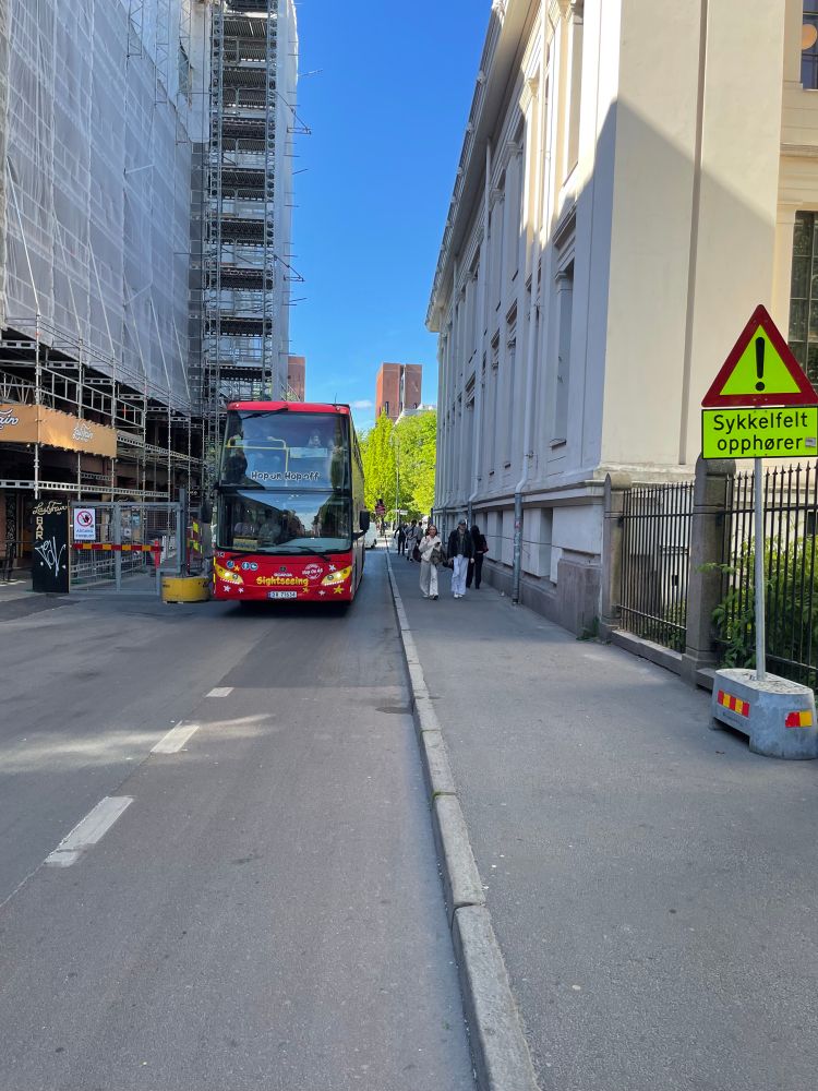 Motgående dobbeltdekker buss delvis i sykkelfeltet. Fortau til høyre med svært høy fortauskant, og skilt med «sykkelfelt opphører», men uten noen alternativ plass å gjøre av seg.