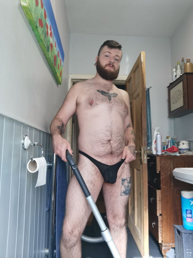 Photo of me in a black thong holding a vaccum cleaner. You can just faintly make out my chastity cage under the thong 
