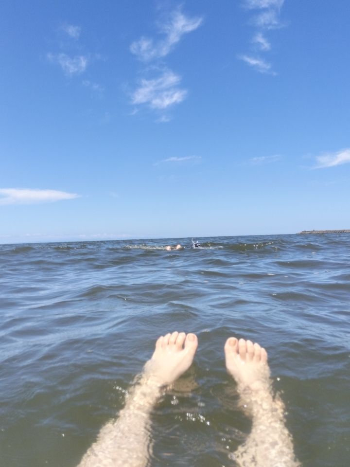 青空と、海水に浮かぶ脚の写真。
雨の影響で水が濁っている。