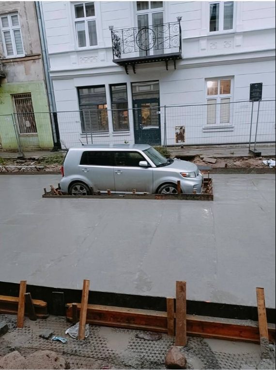 Car surrounded by concrete left there by workers.