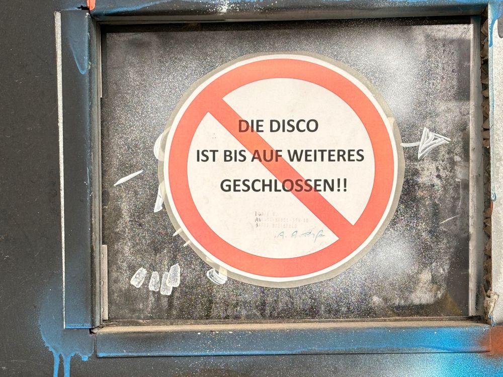 Clubtüre mit einem Verbotsschild, auf dem steht "DIE DISCO IST BIS AUF WEITERES GESCHLOSSEN"