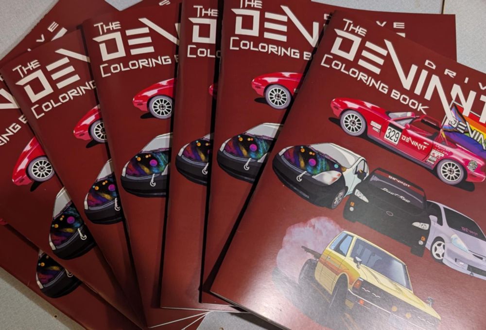 A pile of red drive Deviant coloring books with several cars depicted on the covers