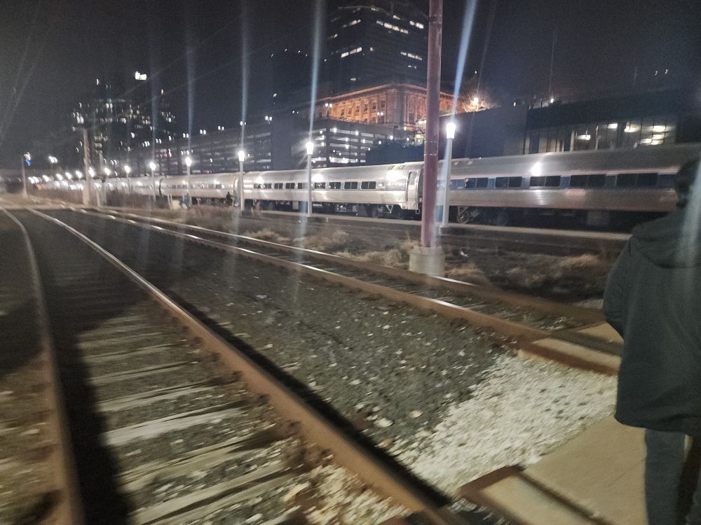 A picture of passenger train cars beneath a nighttime city skyline.