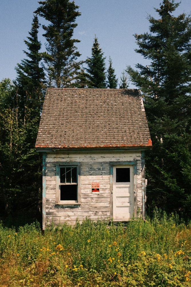 A straight-on photo of a small abandoned cabin.  