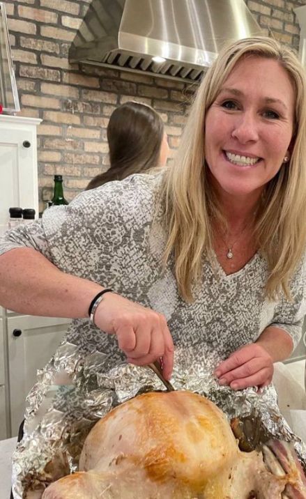 A pic from last year of MTG with a hideous smile peeling the foil back off a turkey and cutting into it. Because the color of her dress is so close to the color of the foil, it almost looks like she's lifting up her dress and the turkey is her pot belly which she's stabbing into with a small knife 