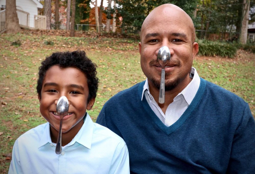 two people balancing spoons on their noses