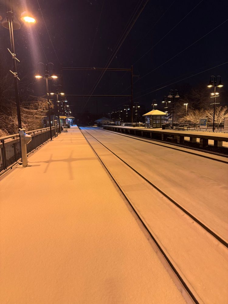 This is a SEPTA station on the outskirts of Philadelphia after a winter storm. Snow covers the platform and the inbound tracks, undisturbed by passengers or trains. A muffled silence surrounds the viewer, and the world is still