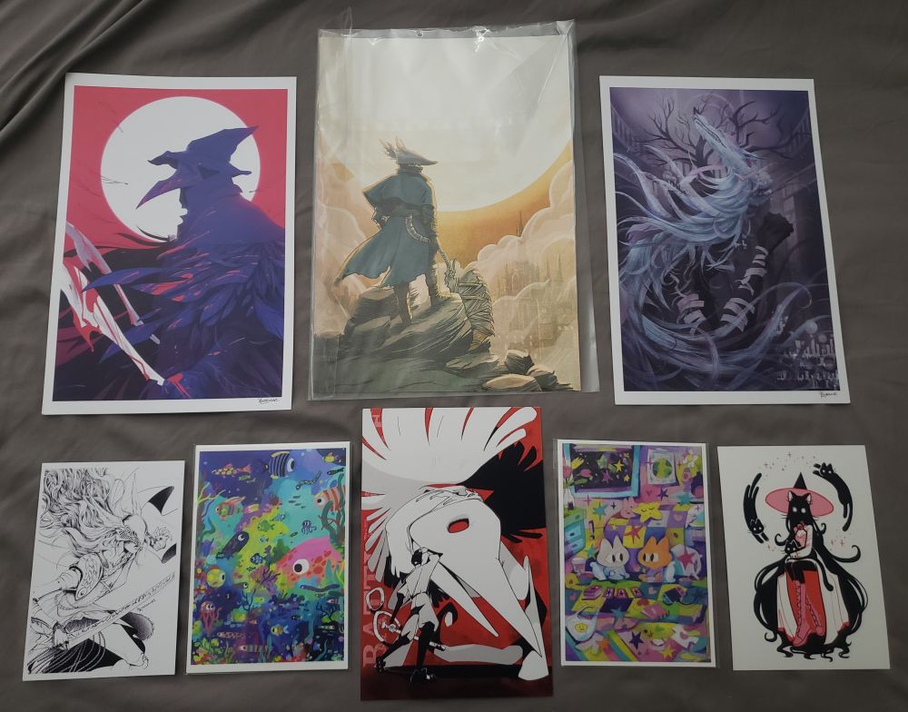 2 rows of 8 prints of various sizes. 3 large prints of Bloodborne characters make up the top row, and the bottom row is made up of smaller various prints. 