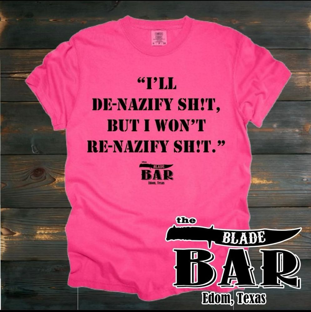 A pink tee sold by The Blade Bar in Edom Texas, saying “I’ll de-nazify sh*t, but I don’t re-nazify sh*t” 