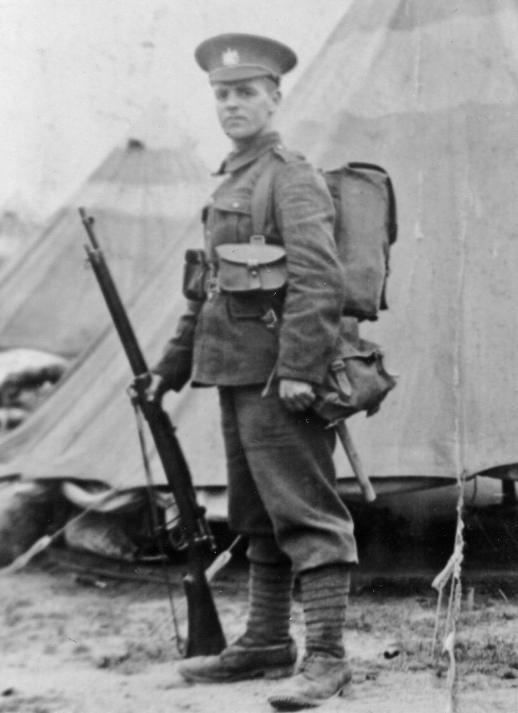 Picture of a World War One soldier with rifle in front of tent