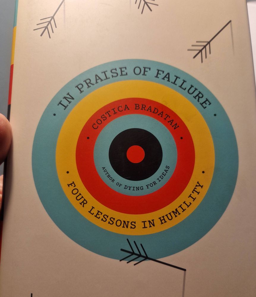 Cover of In Praise of Failure: Four Lessons in Humility by Costica Bradatan. The cover design is a target with the text curving around the rings, surrounded by arrows.