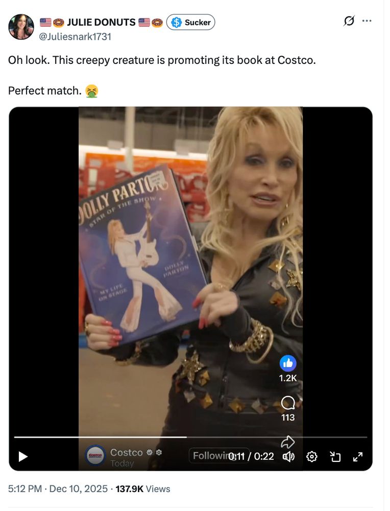 Dolly Parton, who is awesome, holding up a book in Costco.

Tweet from Julie Donuts an X user with over 170K followers: Oh look. This creepy creature is promoting its book at Costco. 

Perfect match