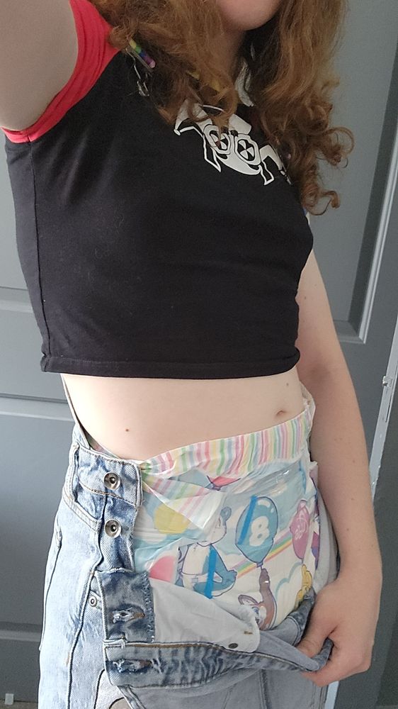 A woman lowers her shortalls to show a tiny tails diaper