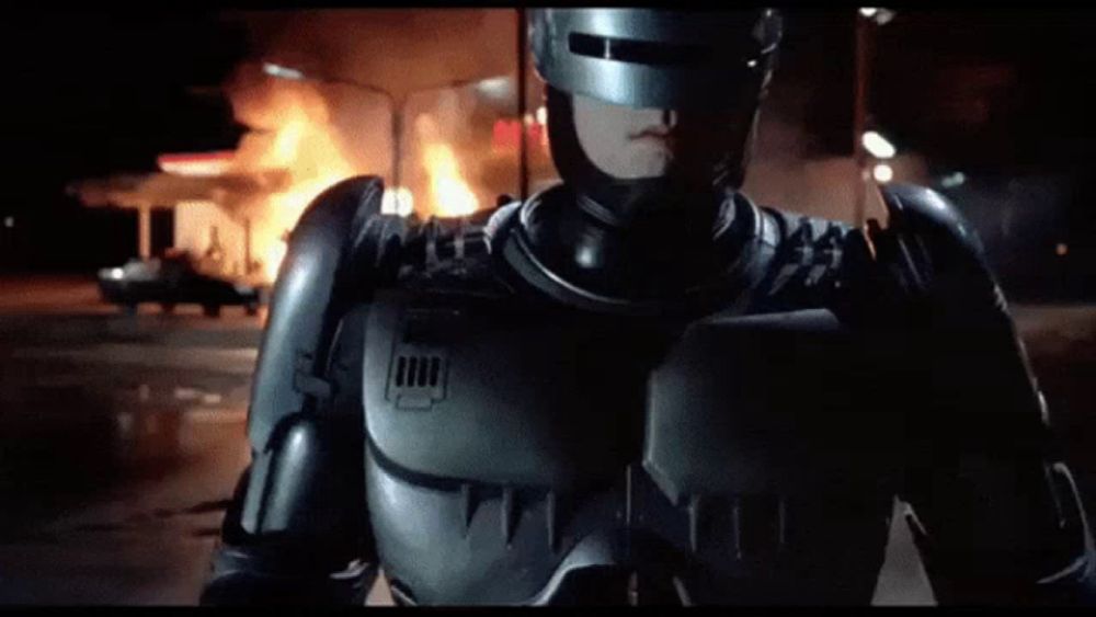 a man in a robot costume stands in front of a fire