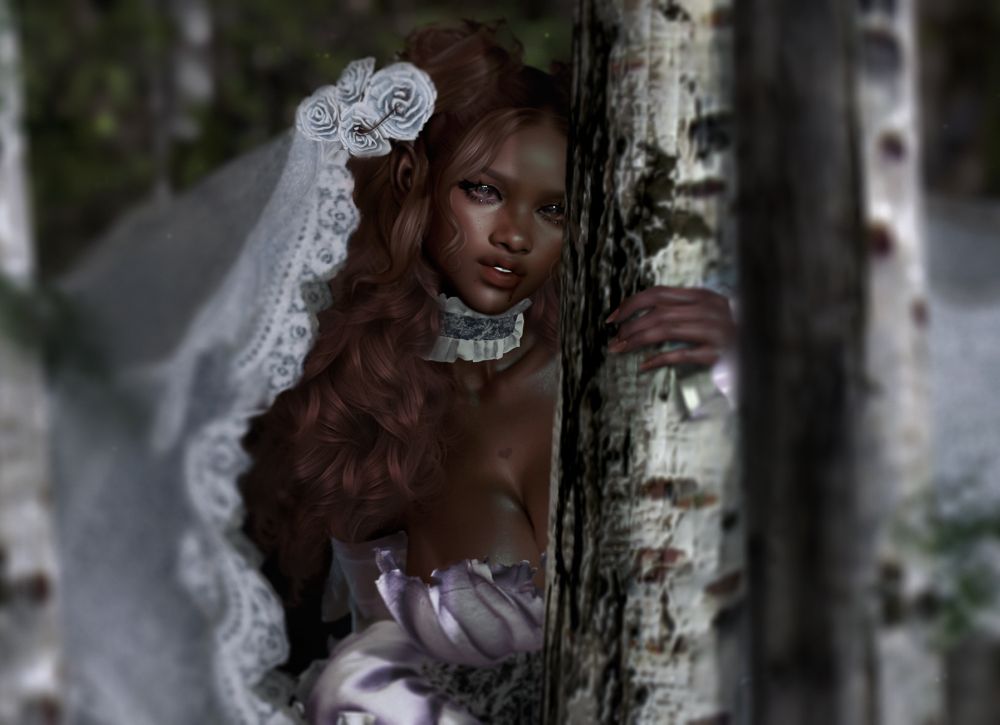 Lady in bridal dress and veil standing by the trees. 
