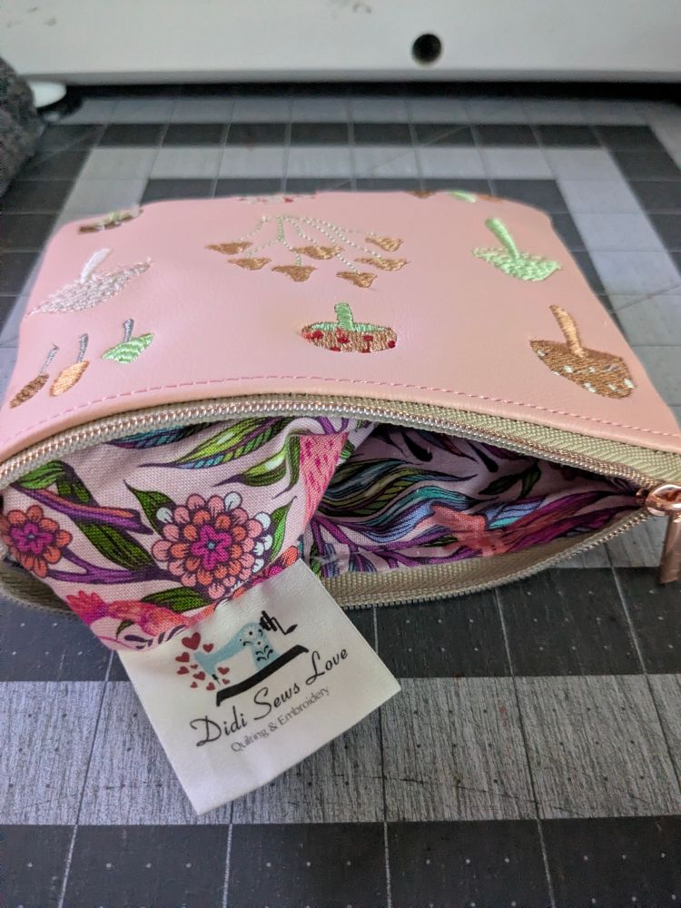 The same bag laying on its side with the lining peeking out from the zipper with my Didi Sews Love label sticking out. 