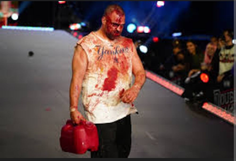 A bloody man carrying a gas can walking toward a wrestling ring. 