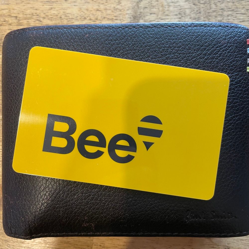 A yellow public transport card. The word Bee and a map pin with stripes like a bee‘s abdomen in black.