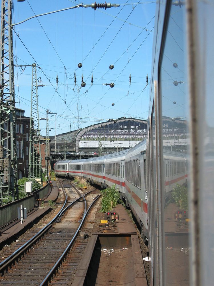 A train pulls into Hamburg Central Station in daylight.