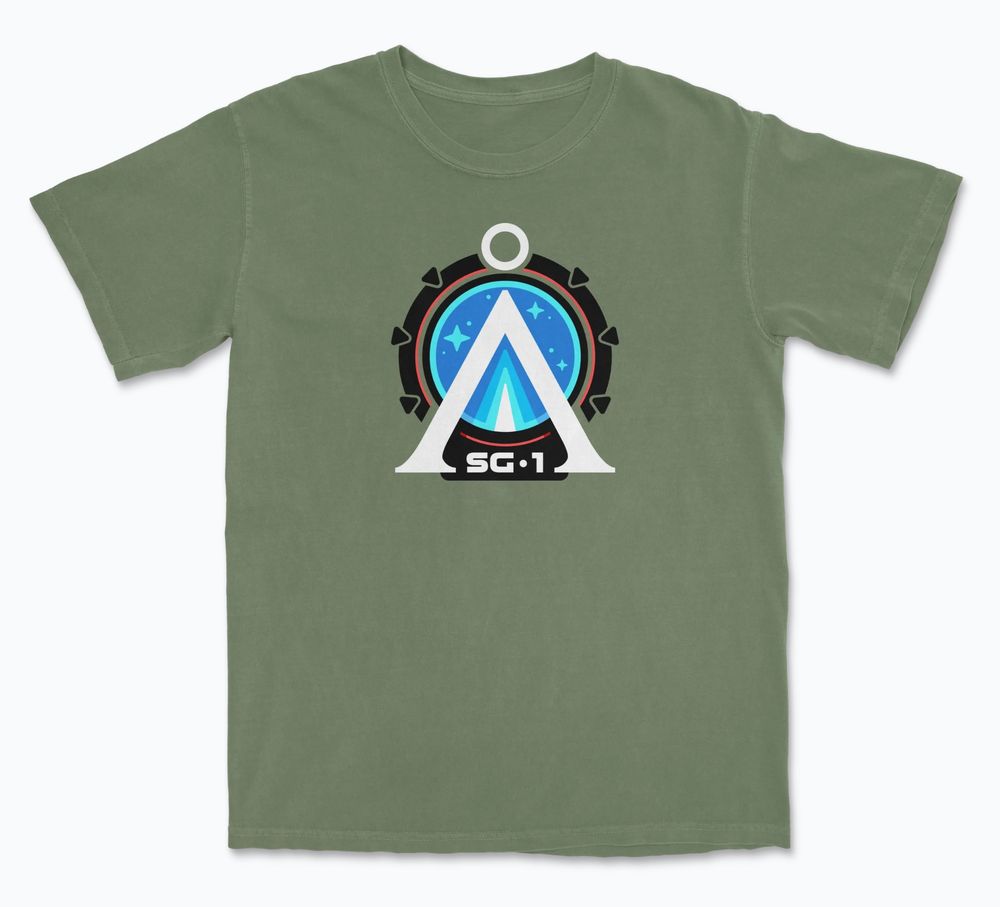 Graphic T-shirt showing the Earth Chevron in white against a black Stargate with the letters SG-1 at the bottom. Shown on a army green shirt.