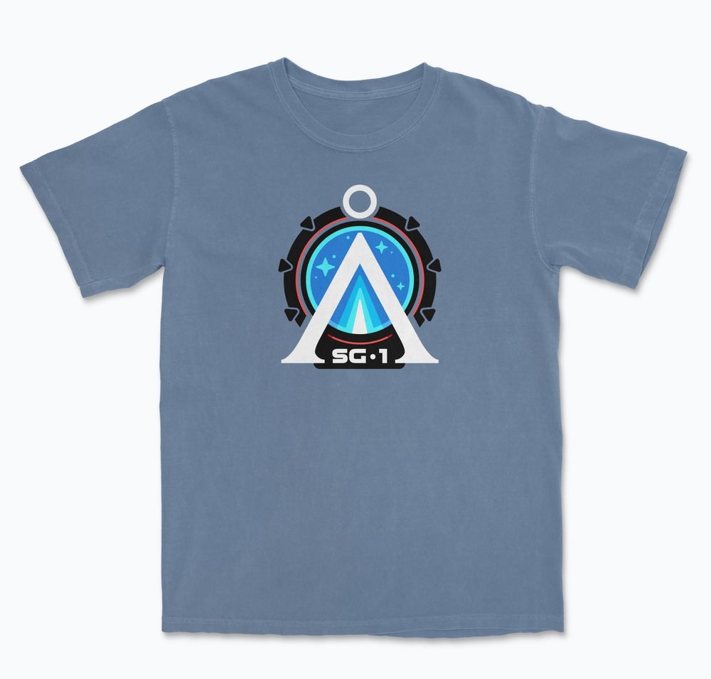 Graphic T-shirt showing the Earth Chevron in white against a black Stargate with the letters SG-1 at the bottom. Shown on a blue shirt.