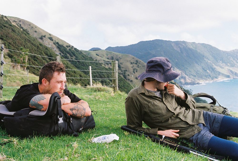 Two people resting and eating gummi snakes at the top of a hill.