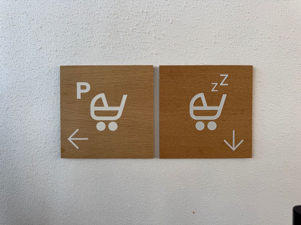 Sign: Pram Parking icon points left. Pram with Zzz icon points down.