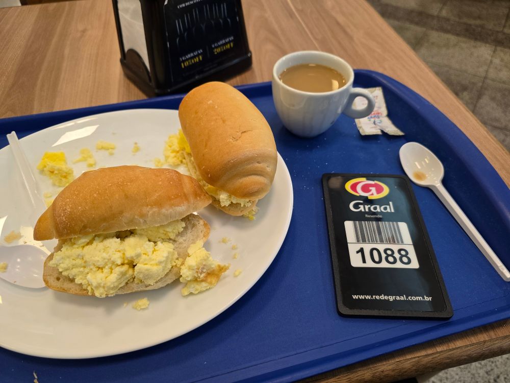 Dois pães com ovo mexido e um copo de café com leite no Grupo Rodoviário Alimentício Augusto Liberato de Resende. O pão estava velho e o ovo estava gelado, mas o café com leite estava padrão hotel.