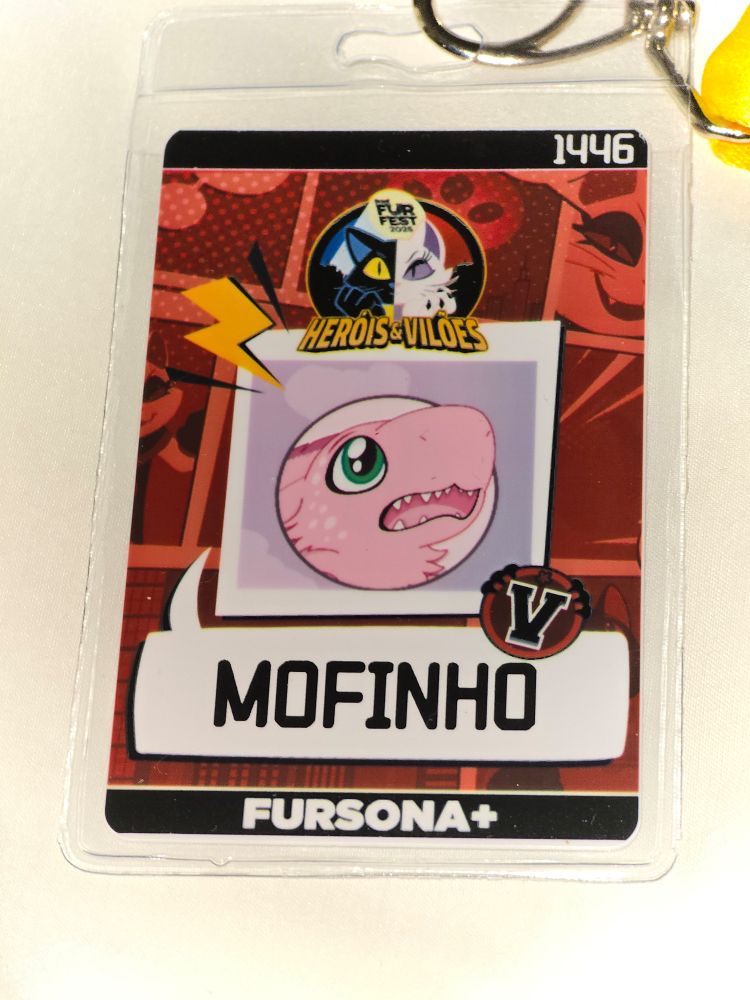 Minha badge da Brasil FurFest 2025. Mofinho é um canary (dragão passarinho) rosa. Vilão acidental, o maior estrambelhado da comunidade. Não sabe o que está acontecendo ou o que fazer no evento.

A arte é por Daieny Schuttz e estava bonitinha, com o círculo centralizado, mas vários participantes ficaram com o corte errado na arte da badge.