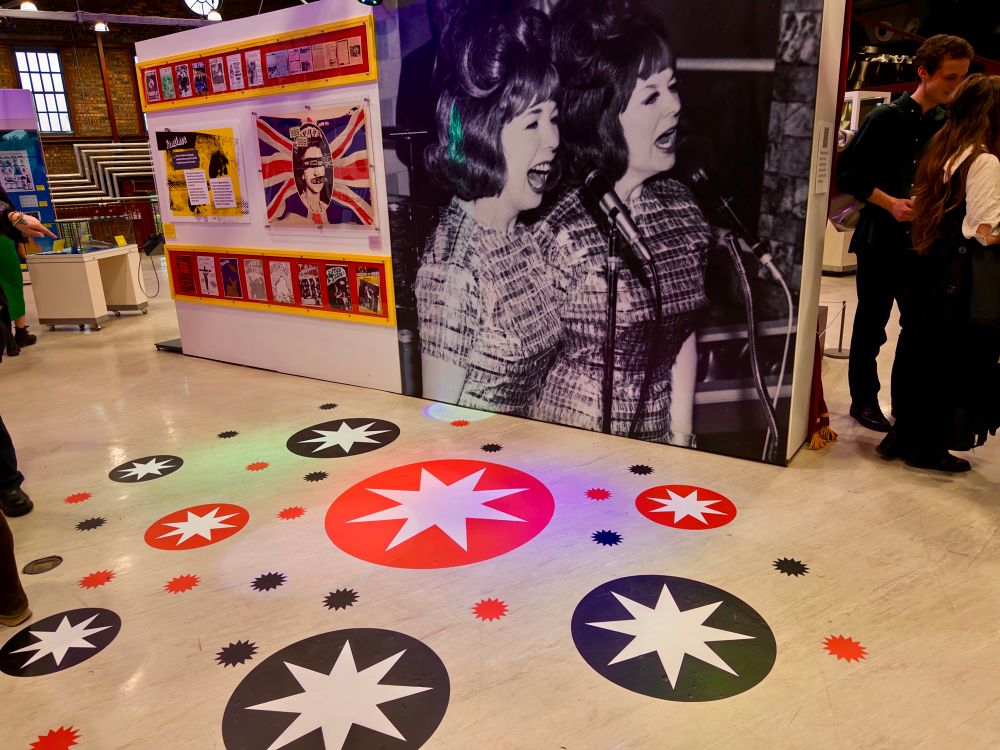 Another view of part of the exhibition showing a dance floor with star graphics on the floor and a big picture of singing sisters Fran and Anna.