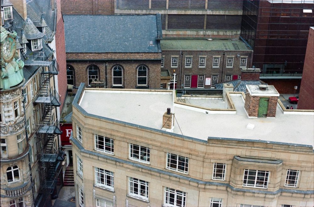 A view looking down on the flat roof of a 1930s sandstone city centre building.
