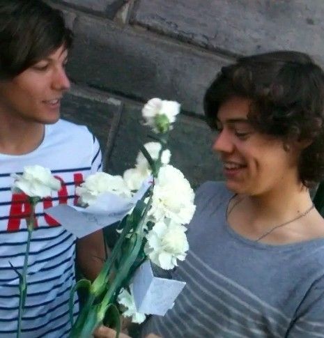 louis tomlinson and harry styles holding some white carnations