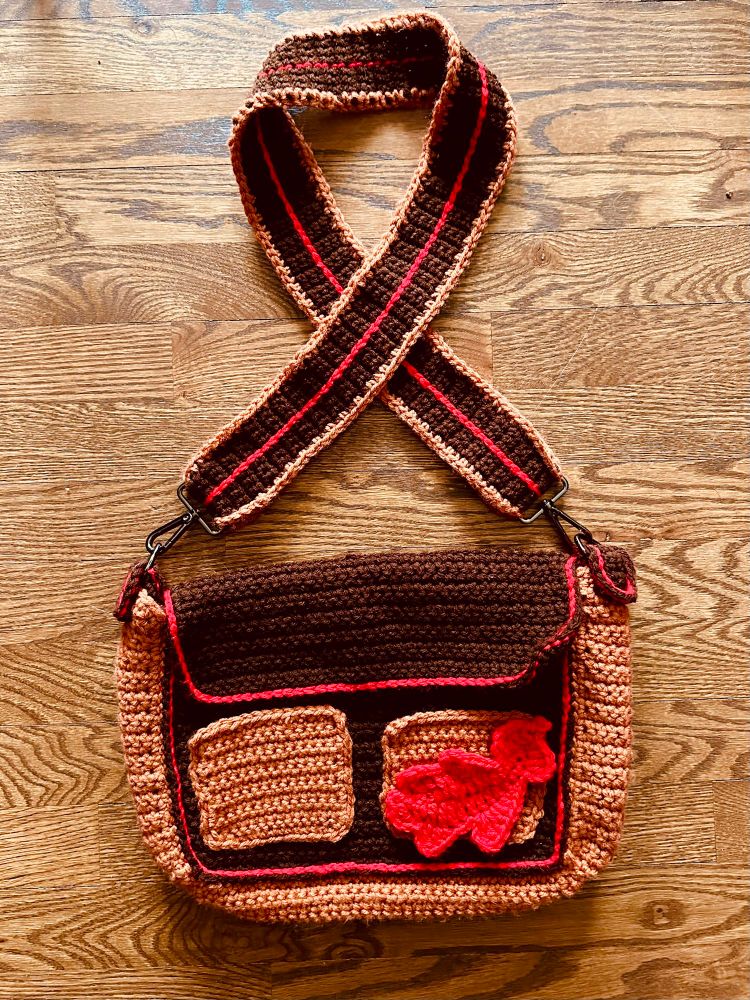 Brown crochet messenger bag with red accents and oak leaf appliqué 