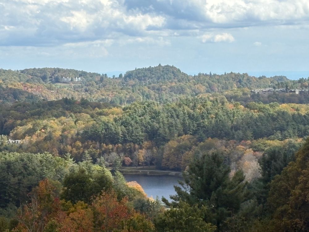 Mountain lake surrounded by hill covered with trees just coming into autumn colors.