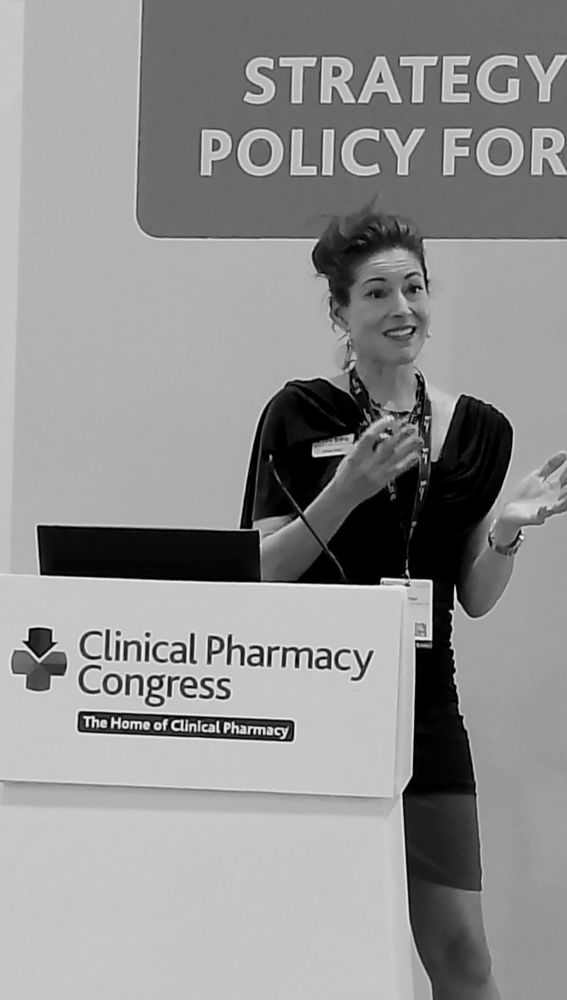 Black and white photo of a woman standing by a conference podium for Clinical Pharmacy Congress 