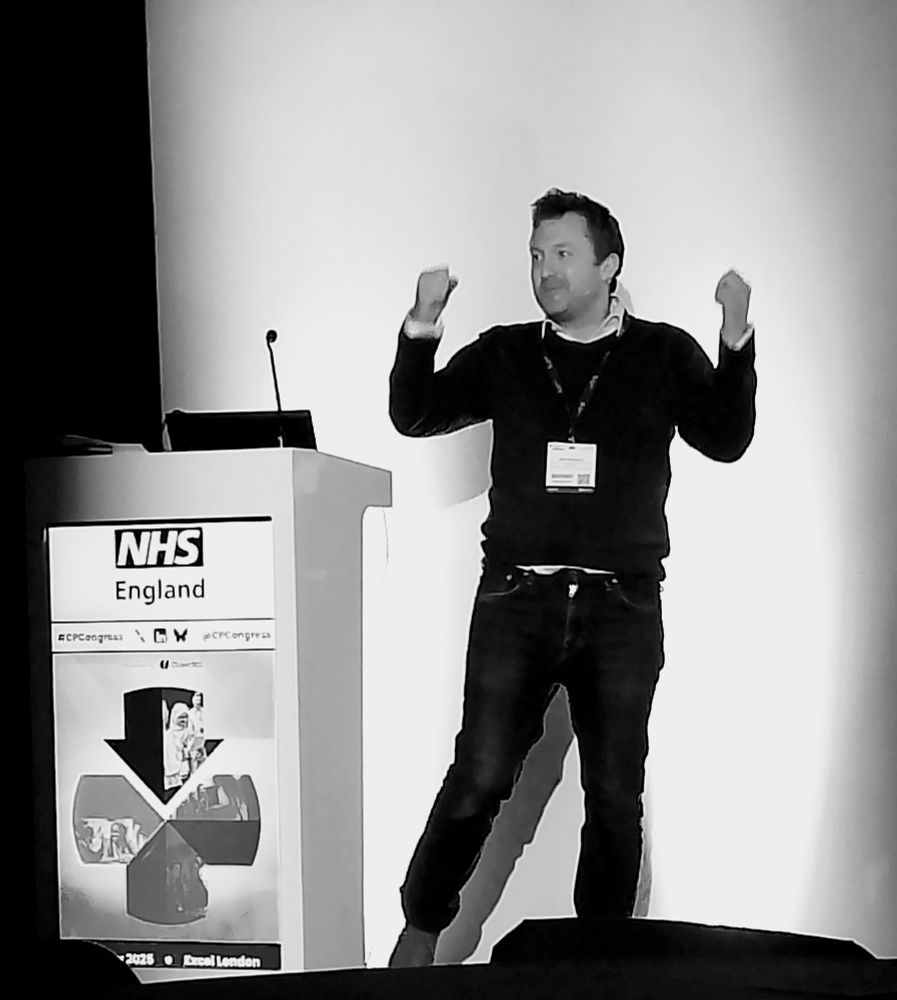A black and white photo of a man with arms raised standing by a conference podium for Clinical Pharmacy Congress 