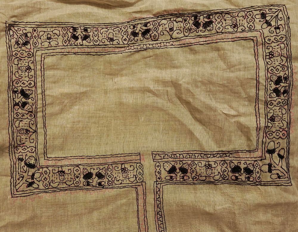 Complex rectangleular collar embroidered entirely in black thread with motifs of acorns and abstract geometrical frame borders. Some border parts are a little less filled in. That's what's left. 