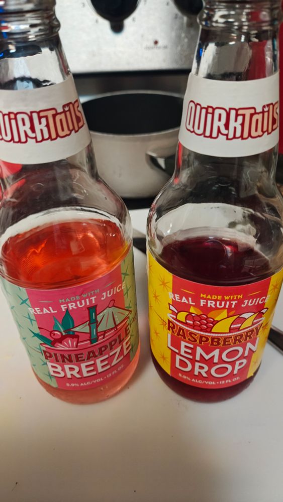 Two glass bottles, one is quirktail in pineapple breeze flavor, the other is raspberry lemon drop they're 5.9% alc/vol. They say they're made with real fruit juice. 
