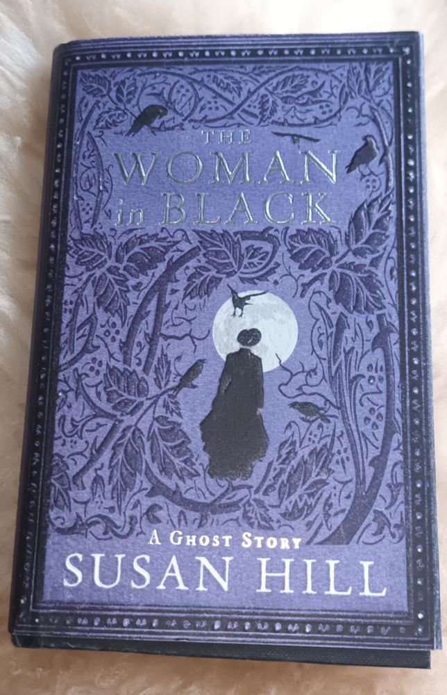 Photo of The Woman in Black book by Susan Hill. Purple cover with black wood etching design and silver writing.