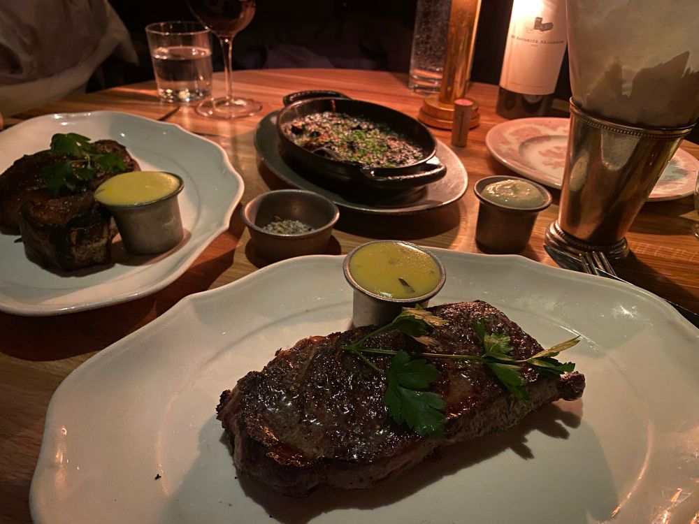 A steak is depicted with a side of béarnaise sauce and a gratin of creamed spinach