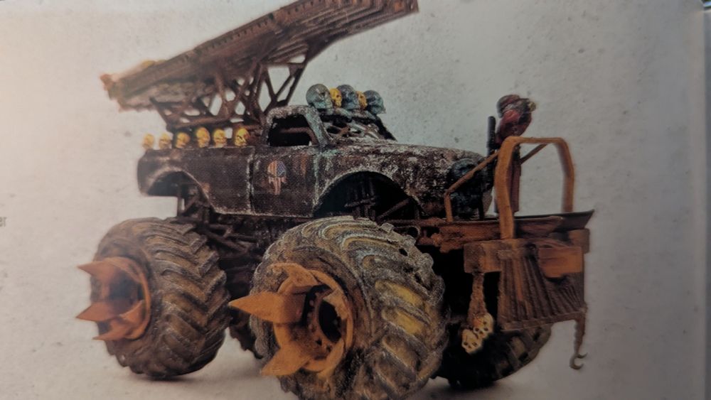 A custom monster truck miniature with an American flag Punisher skull icon on the passenger-side door.