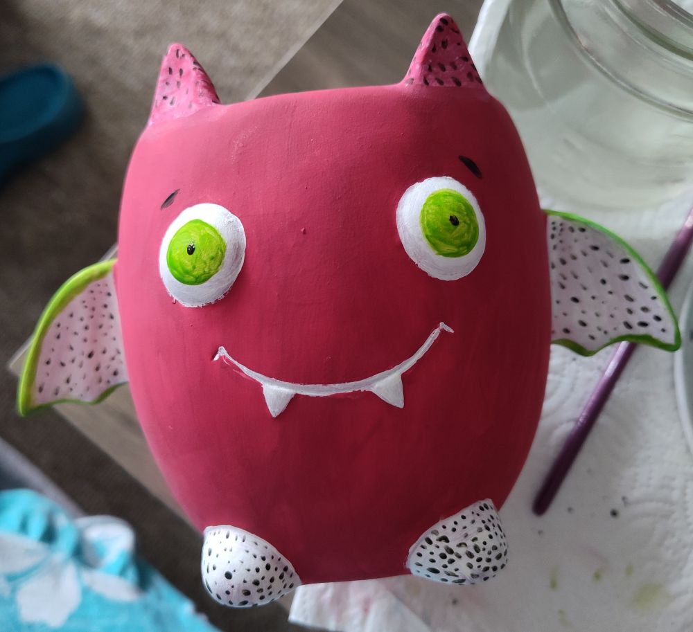 A bat shaped plant pot is painted to look like dragon fruit, dragon fruit bat