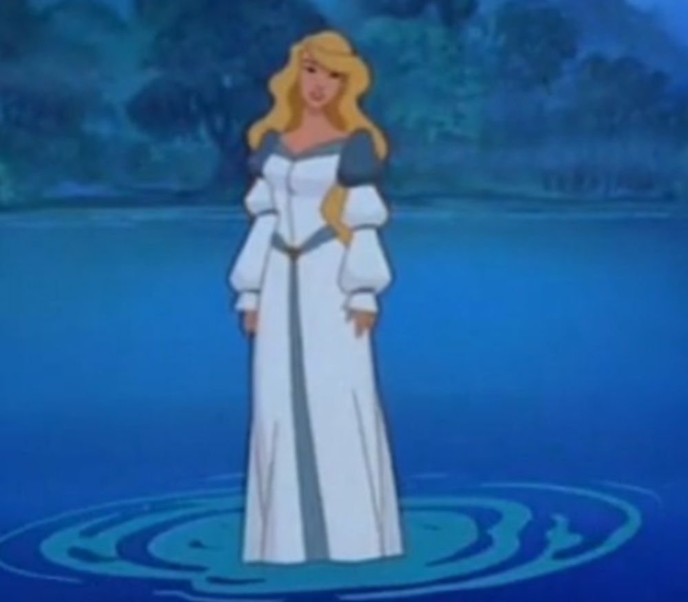 Long haired blonde standing in the middle of a lake in a white long dress with long sleeves and teal accents at the shoulders and belt