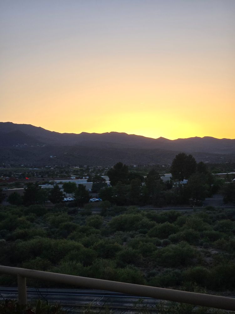 View of mountain ridge 30 miles away at dusk. In-between are scattered buildings of a small town. 