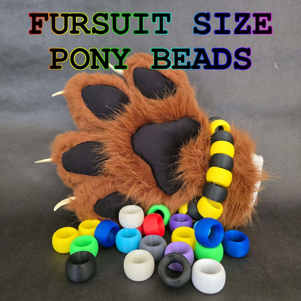 pile of fursuit scale pony beads with a brown and black paw in the background that has a bracelet made of said beads.