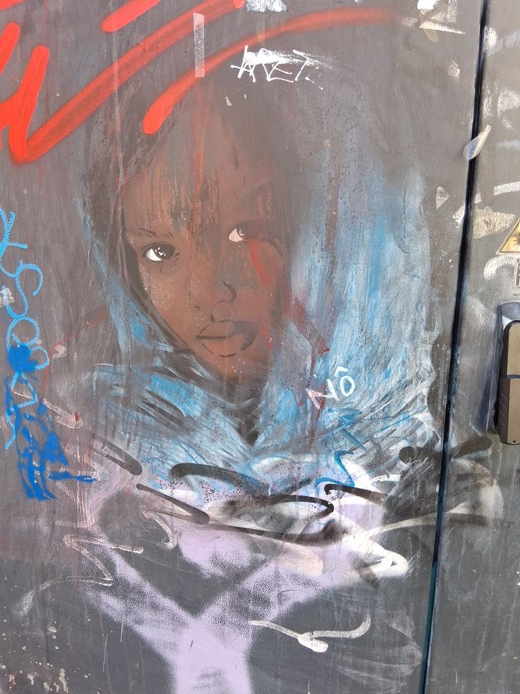 Visage d'une enfant couverte d’un tissu de couleur bleue. 
