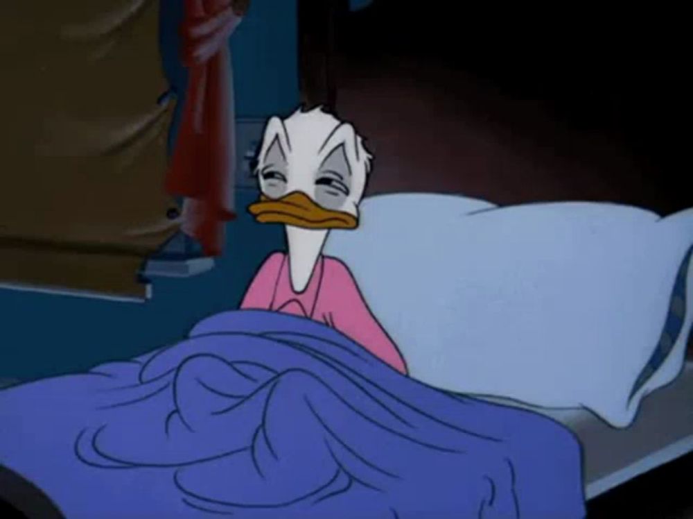 donald duck is laying in bed with his eyes closed and a pink shirt on .