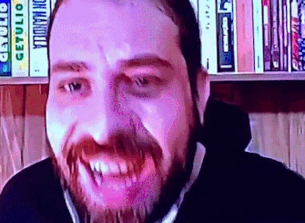 a man with a beard is smiling in front of a bookshelf with a book called dracula on it