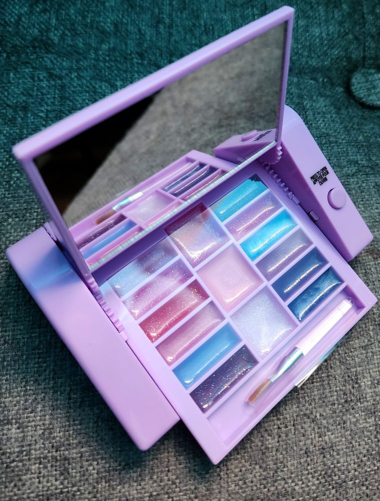 The same little thingy, opened to reveal a mirror, fun lip glosses, and a little brush